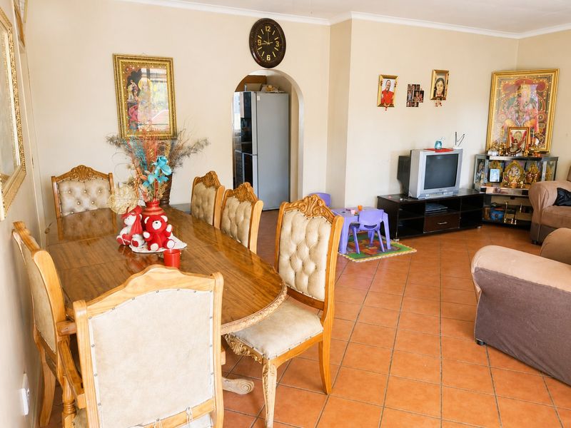 Open plan living and dining area featuring terracotta floor tiles and an arched doorway leading to the kitchen area.