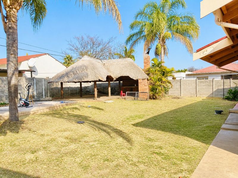 Spacious rear garden featuring a traditional thatched lapa with a built-in brick braai, perfect for outdoor entertaining and relaxation.