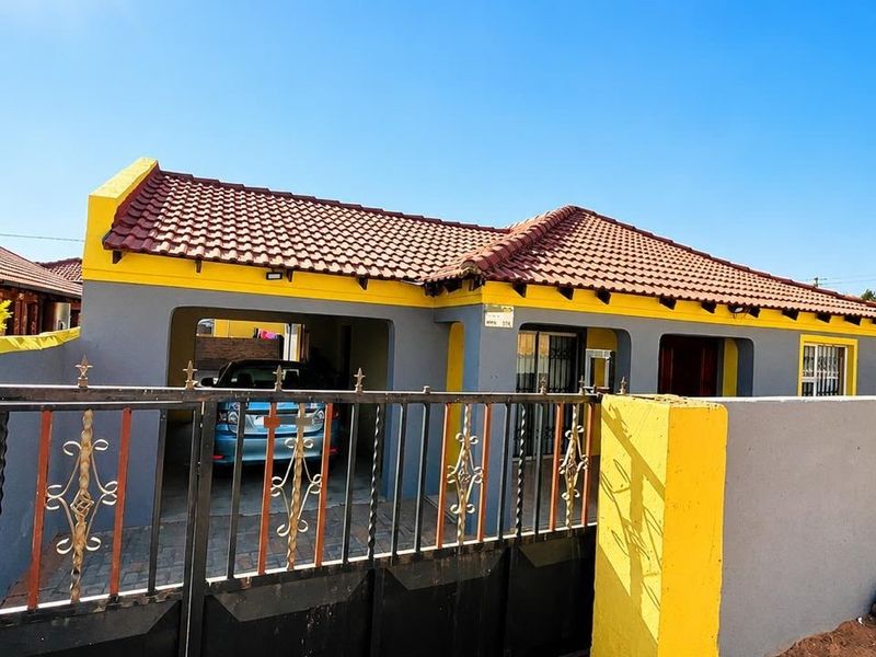 Front view of a single-story house featuring a tiled roof, a secure wrought iron gate, and a covered carport area.