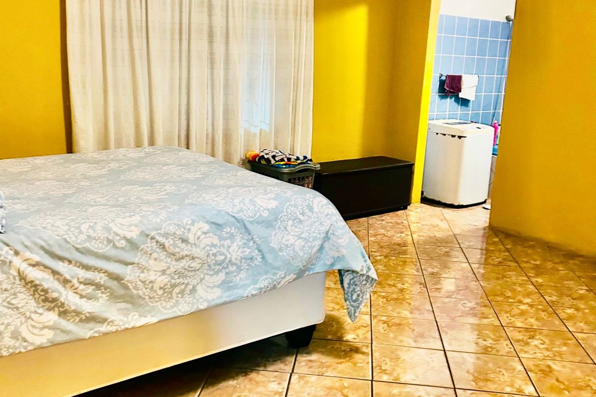 Bedroom featuring tiled flooring and direct access to an en-suite bathroom, requiring cosmetic updates to the ceiling and wall finishes.
