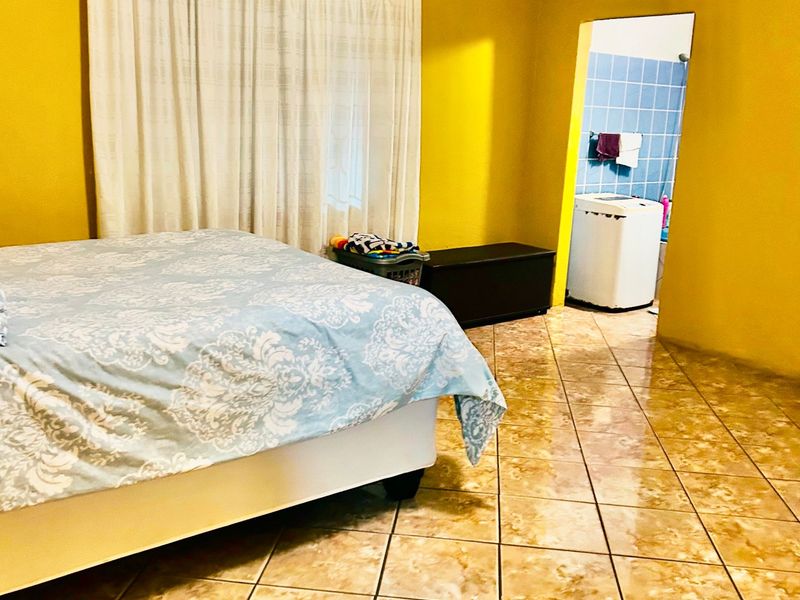 Bedroom featuring tiled flooring and direct access to an en-suite bathroom, requiring cosmetic updates to the ceiling and wall finishes.