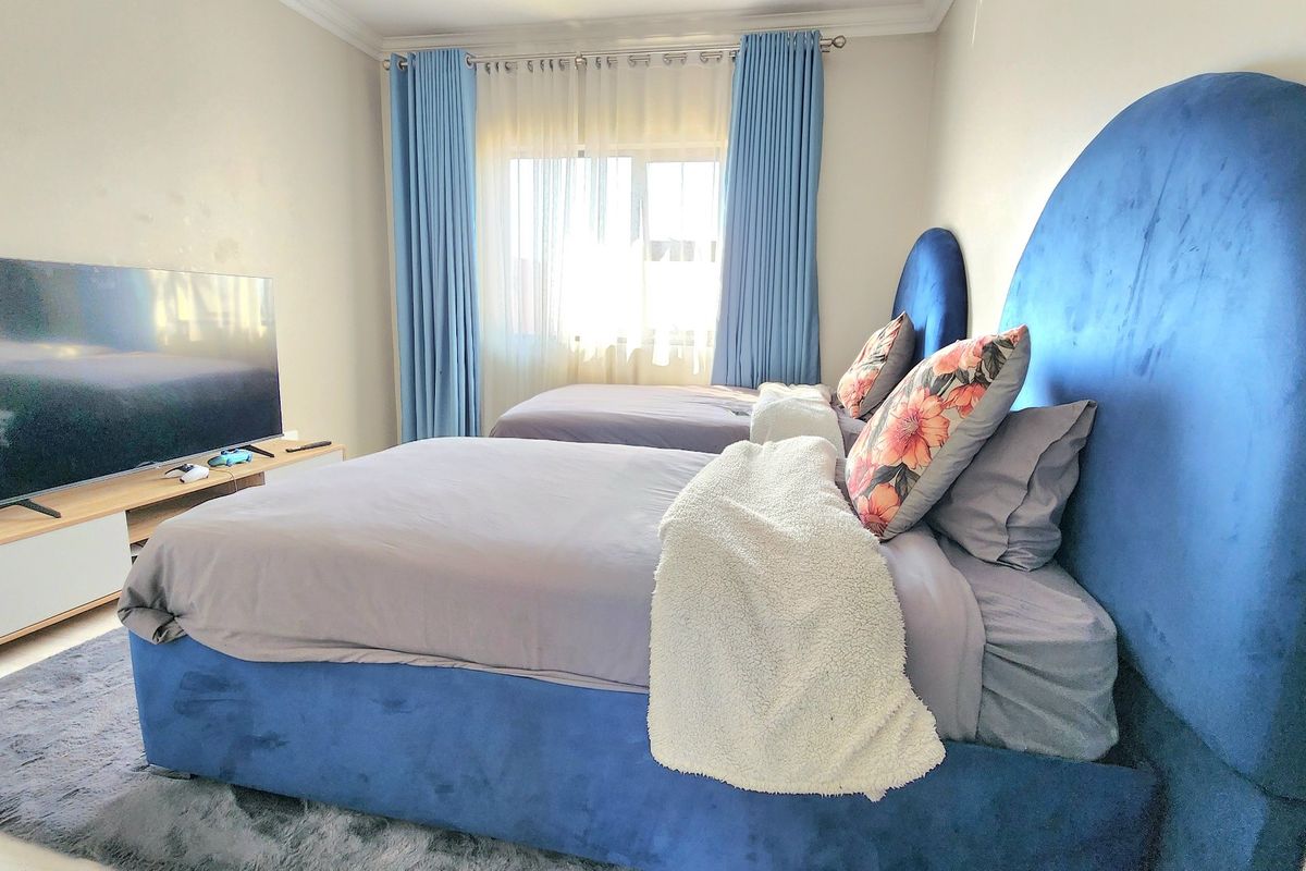 A well-maintained bedroom featuring neutral wall finishes, decorative cornice detailing, and a window with curtain tracks.