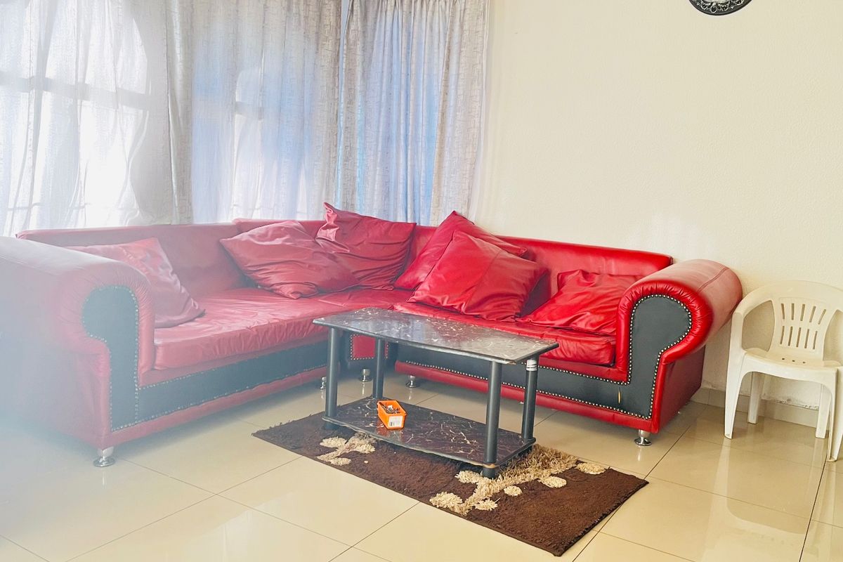 A living room area featuring tiled flooring and large windows with curtains.