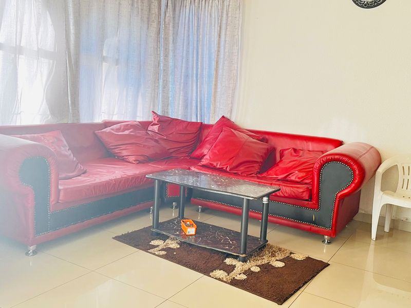 A living room area featuring tiled flooring and large windows with curtains.