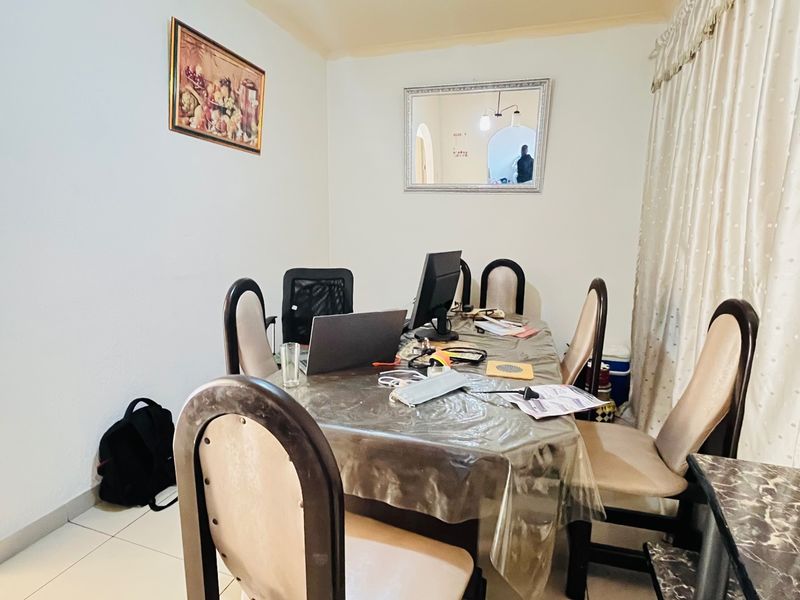 A functional dining room featuring tiled flooring and an arched entryway, providing a neutral space suitable for various interior design styles.