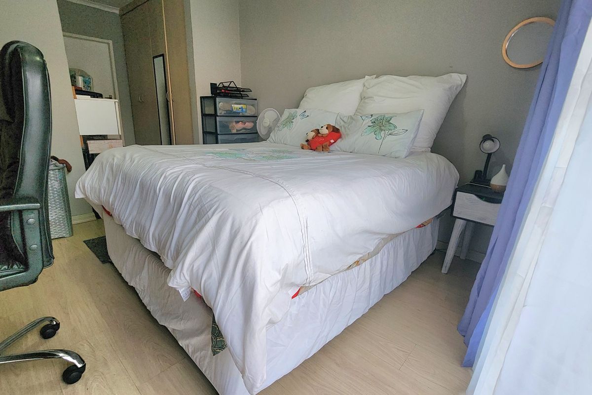 A functional bedroom featuring light-toned laminate flooring and built-in cupboard storage, providing a neutral base for personalization.