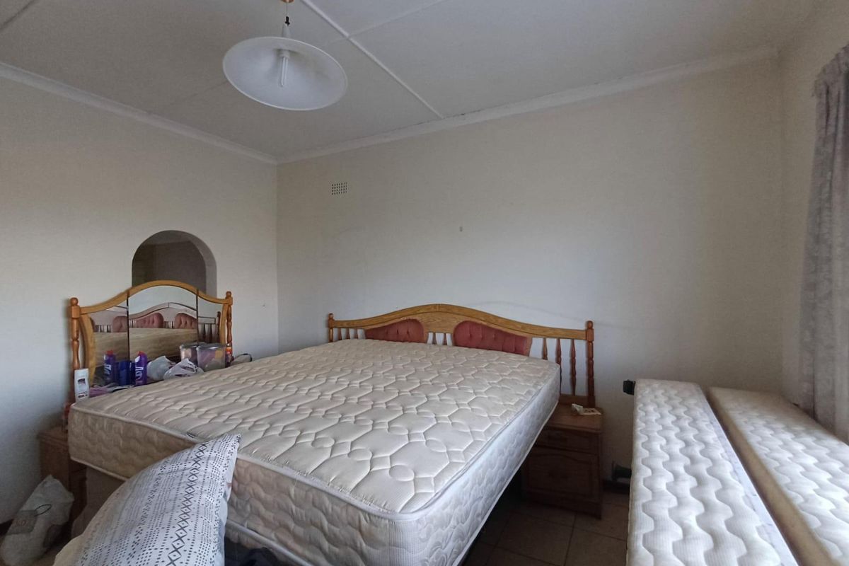 A bedroom featuring tiled flooring and a distinctive arched wall opening, requiring cosmetic updates to the ceiling and finishes.