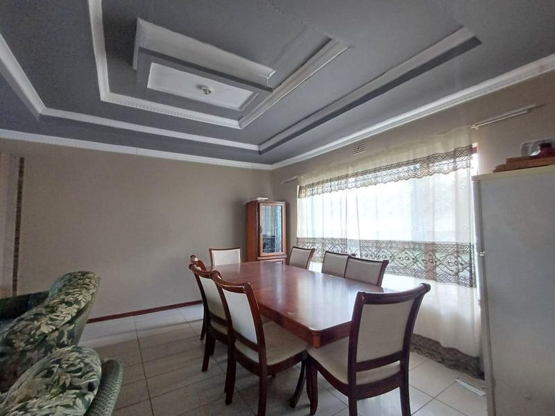 A dining room featuring a decorative tray ceiling, tiled flooring, and large windows allowing for natural light.