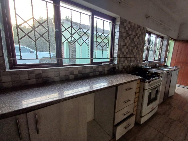 A functional kitchen featuring granite countertops, tiled backsplash, and built-in cabinetry, requiring some maintenance and cosmetic updates to modernize the space.