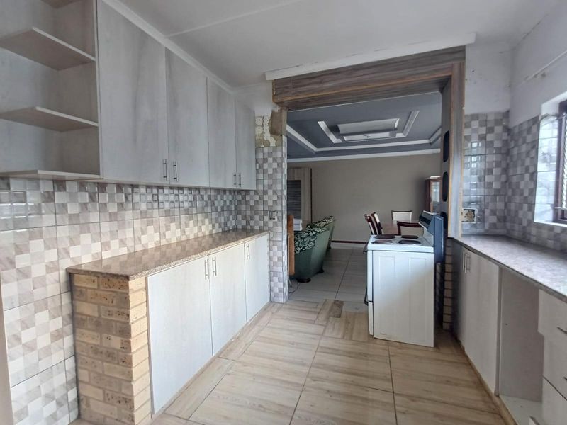 Kitchen featuring built-in cabinetry, tiled backsplash, and stone countertops, with an open-plan layout leading into the adjacent living area.