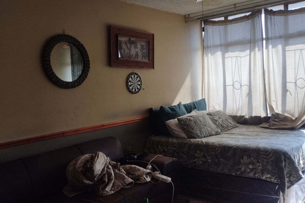 A bedroom featuring a large window with natural light, requiring cosmetic updates to the walls and ceiling to improve the overall aesthetic.