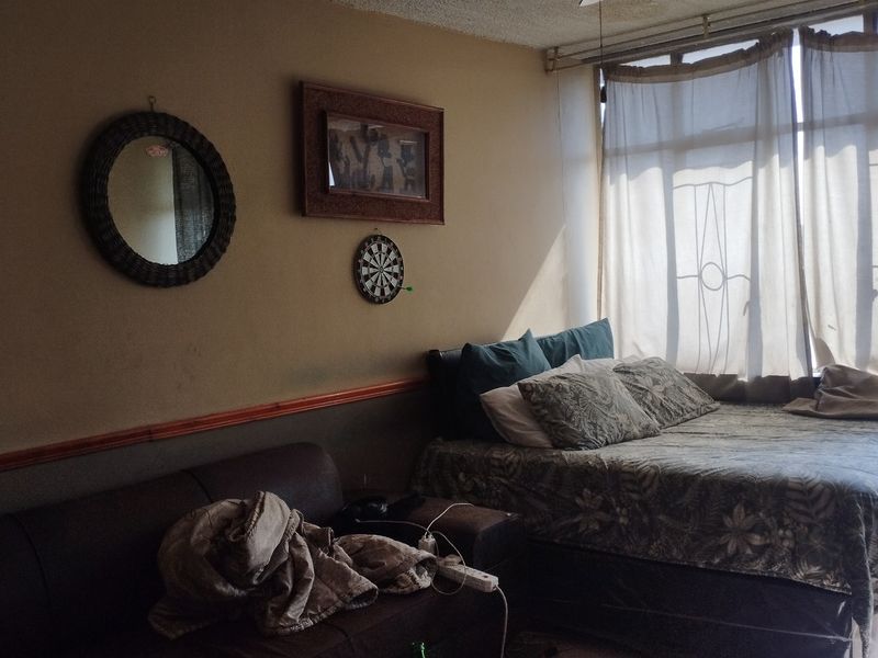 A bedroom featuring a large window with natural light, requiring cosmetic updates to the walls and ceiling to improve the overall aesthetic.