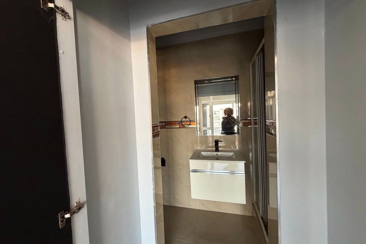 A modern bathroom featuring a wall-mounted vanity with basin, tiled walls, and a shower enclosure.