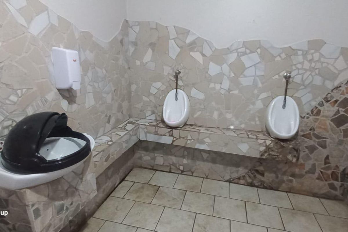 Commercial bathroom facility featuring wall-mounted urinals and decorative stone-style wall tiling with tiled flooring.