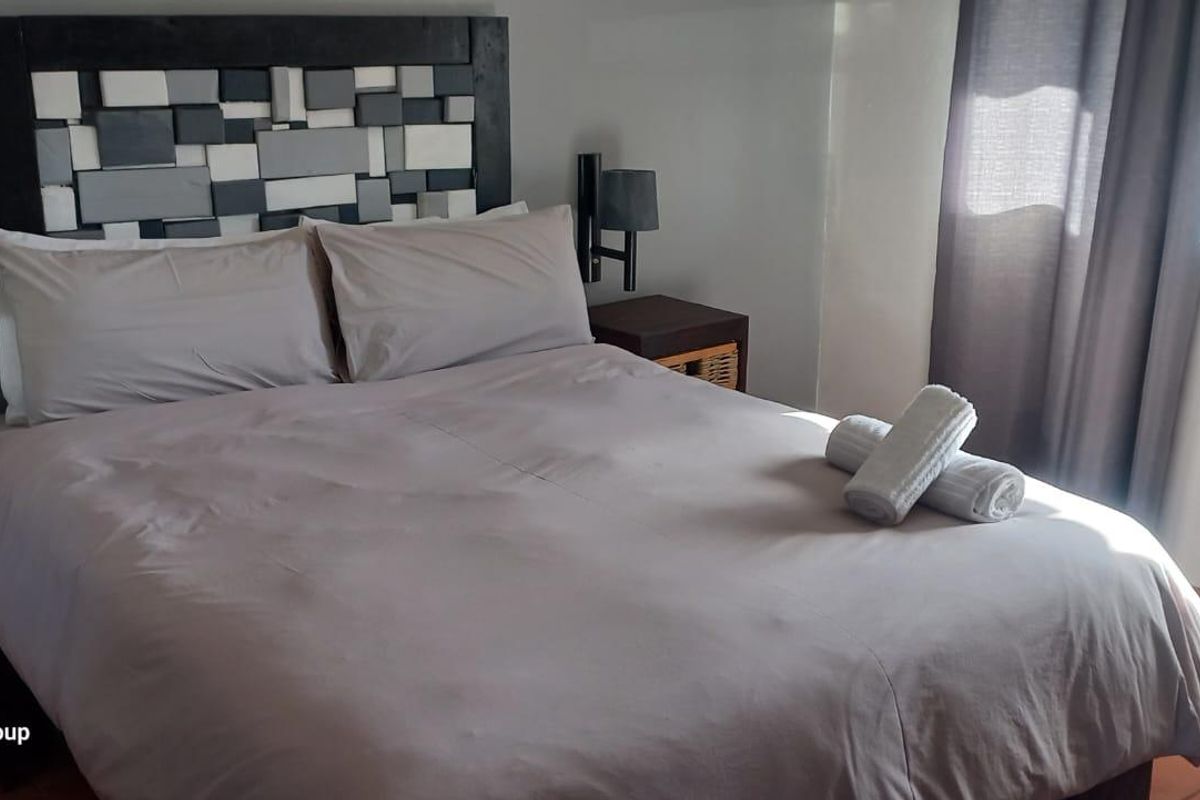 A bedroom featuring terracotta floor tiles and wall-mounted bedside lighting fixtures.