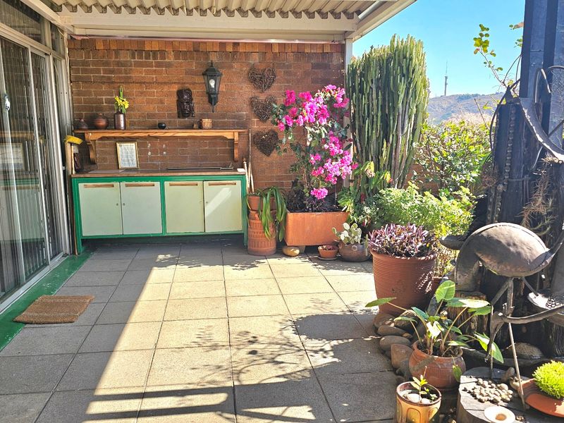 A covered outdoor patio featuring exposed brick walls, tiled flooring, and built-in cabinetry, providing a functional space for outdoor living and entertaining.