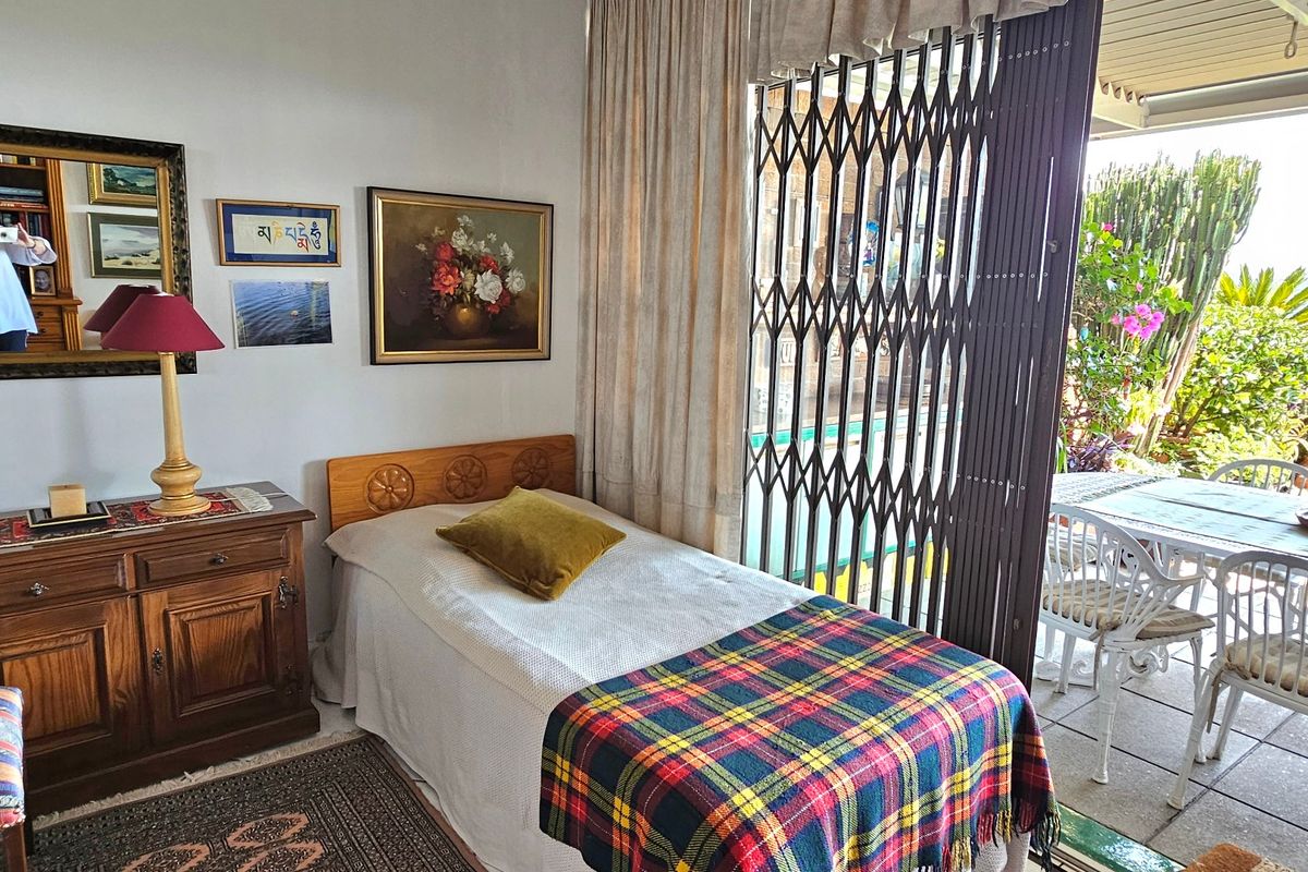 A bedroom featuring a sliding security gate providing direct access to an outdoor patio area.