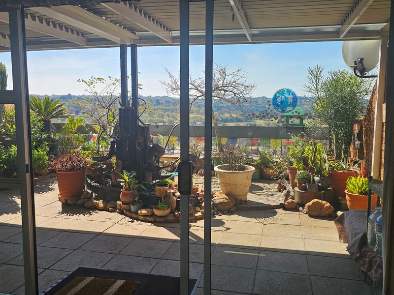 A spacious covered balcony featuring tiled flooring, a metal roof structure, and scenic elevated views, providing a pleasant outdoor living space.