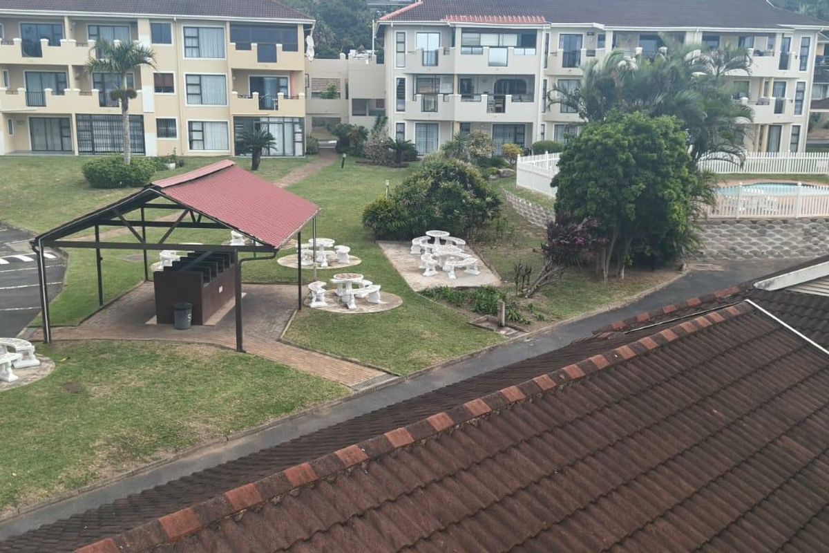 Aerial view of the apartment complex grounds featuring communal gardens, a covered braai area, and a swimming pool with paved surroundings.