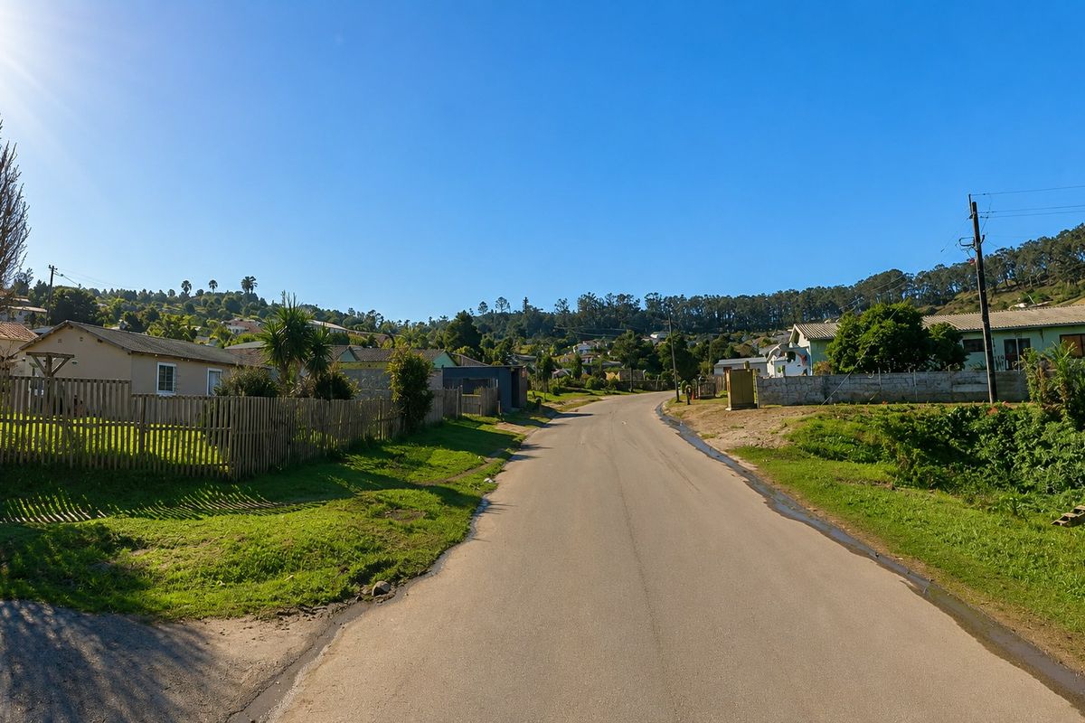 A view of a residential street showing surrounding houses, boundary fencing, and local infrastructure under a clear blue sky.