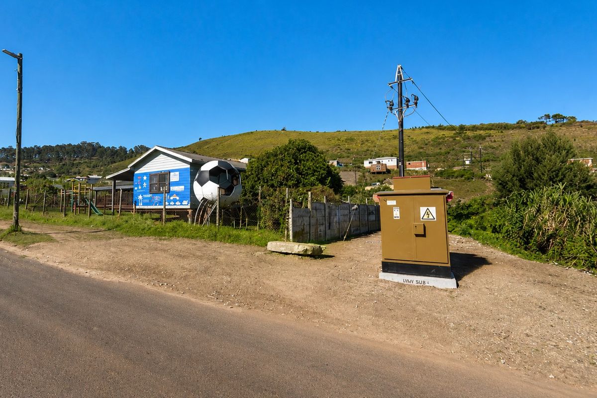 Street view showing a local electrical substation, utility infrastructure, and adjacent property boundary fencing in a rural or semi-rural setting.