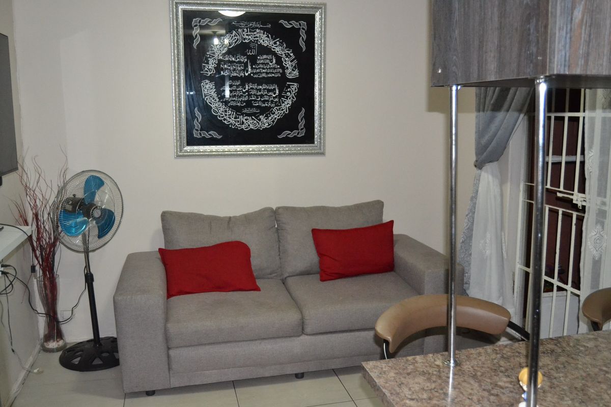 A living area featuring tiled flooring and a security gate, providing a functional space for relaxation.