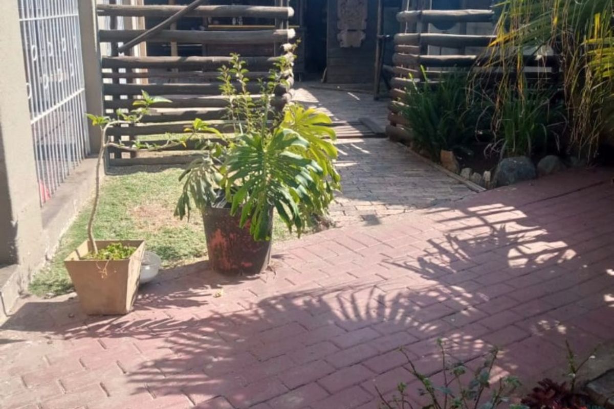 Rear garden area featuring brick paving and a traditional thatched lapa structure, providing an outdoor entertainment space.