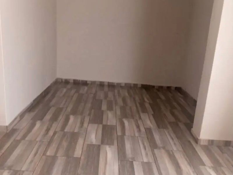 An empty, neutral-toned room featuring modern wood-look floor tiles, providing a blank canvas for interior design and furnishing.