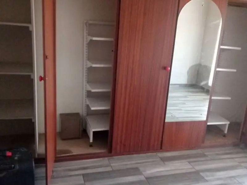 Bedroom featuring a large built-in wooden wardrobe with integrated shelving and a mirrored panel, complemented by modern wood-look laminate flooring.
