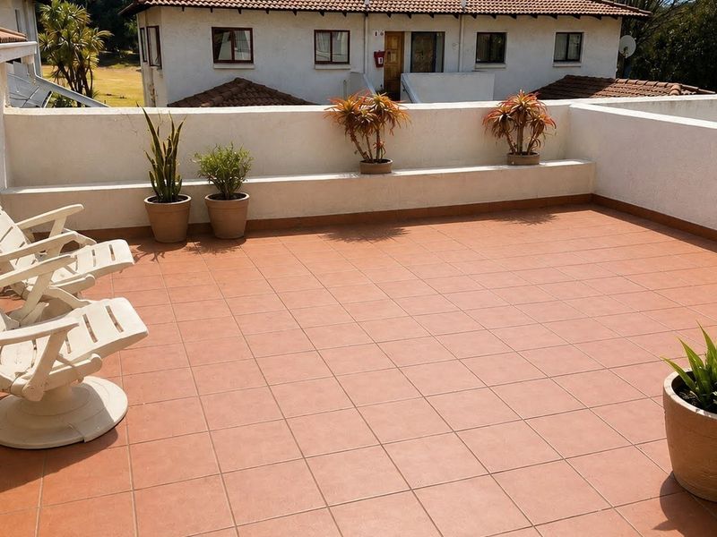 A spacious open-air balcony featuring terracotta-style floor tiles and a built-in planter ledge, offering a functional outdoor entertainment area.
