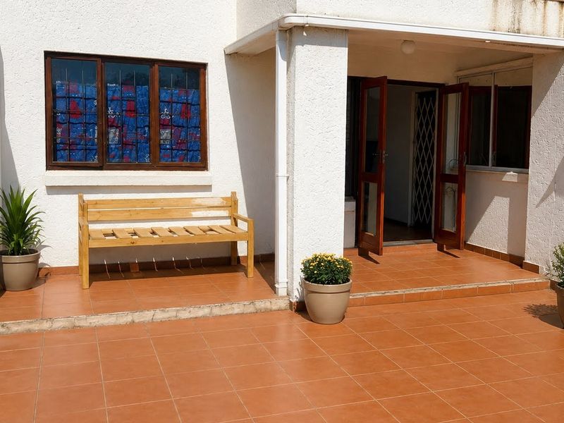 A covered patio area featuring terracotta tiled flooring, providing a functional outdoor space with direct access to the interior of the townhouse.