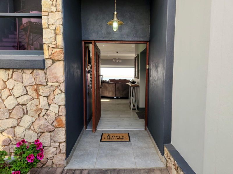 Inviting front entrance featuring stone cladding, a solid timber door, and a modern pendant light, leading into a bright, open-plan living space.