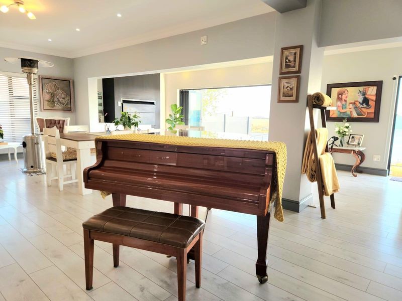 Spacious open-plan living area featuring light laminate flooring, recessed downlighting, and bi-fold doors leading to the exterior, with a built-in fireplace.
