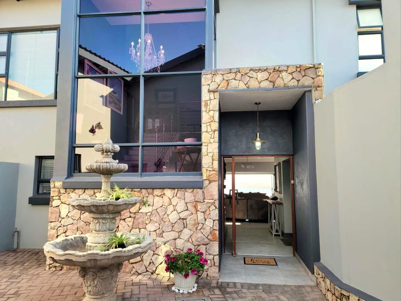 Modern front entrance featuring stone cladding, a large feature window, and a decorative stone fountain, providing an inviting and contemporary facade.