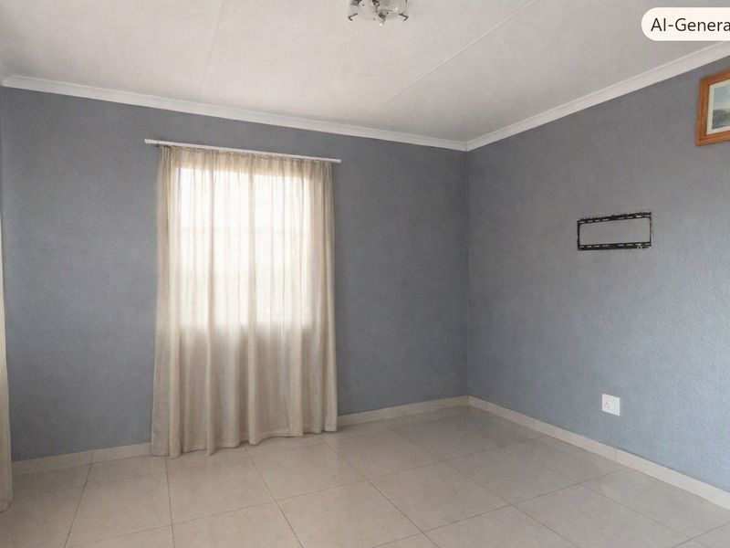 A clean, empty living room featuring neutral grey walls, tiled flooring, and a wall-mounted TV bracket, offering a versatile space for personalization.