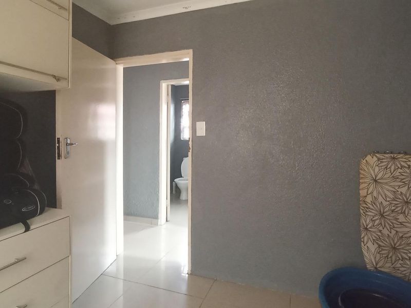 A functional hallway area featuring built-in cabinetry and tiled flooring, providing access to adjacent rooms including a bathroom.