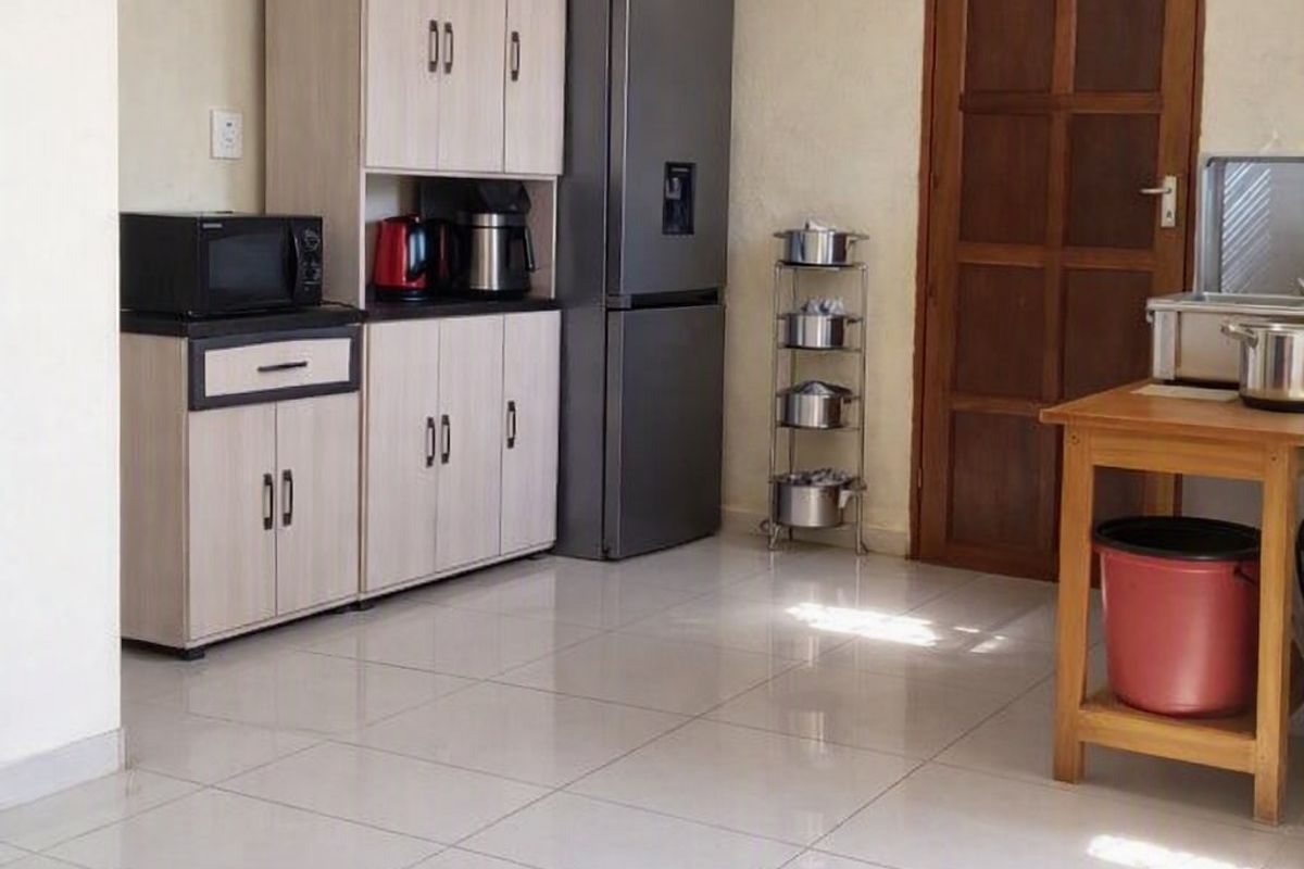 A functional kitchen area featuring light-toned built-in cabinetry, tiled flooring, and a traditional timber door.