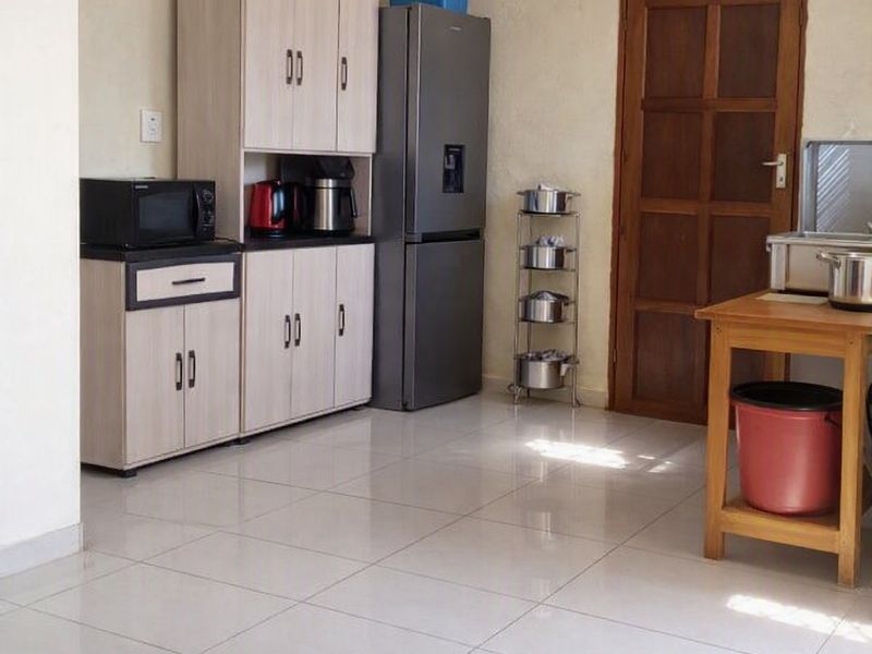 A functional kitchen area featuring light-toned built-in cabinetry, tiled flooring, and a traditional timber door.