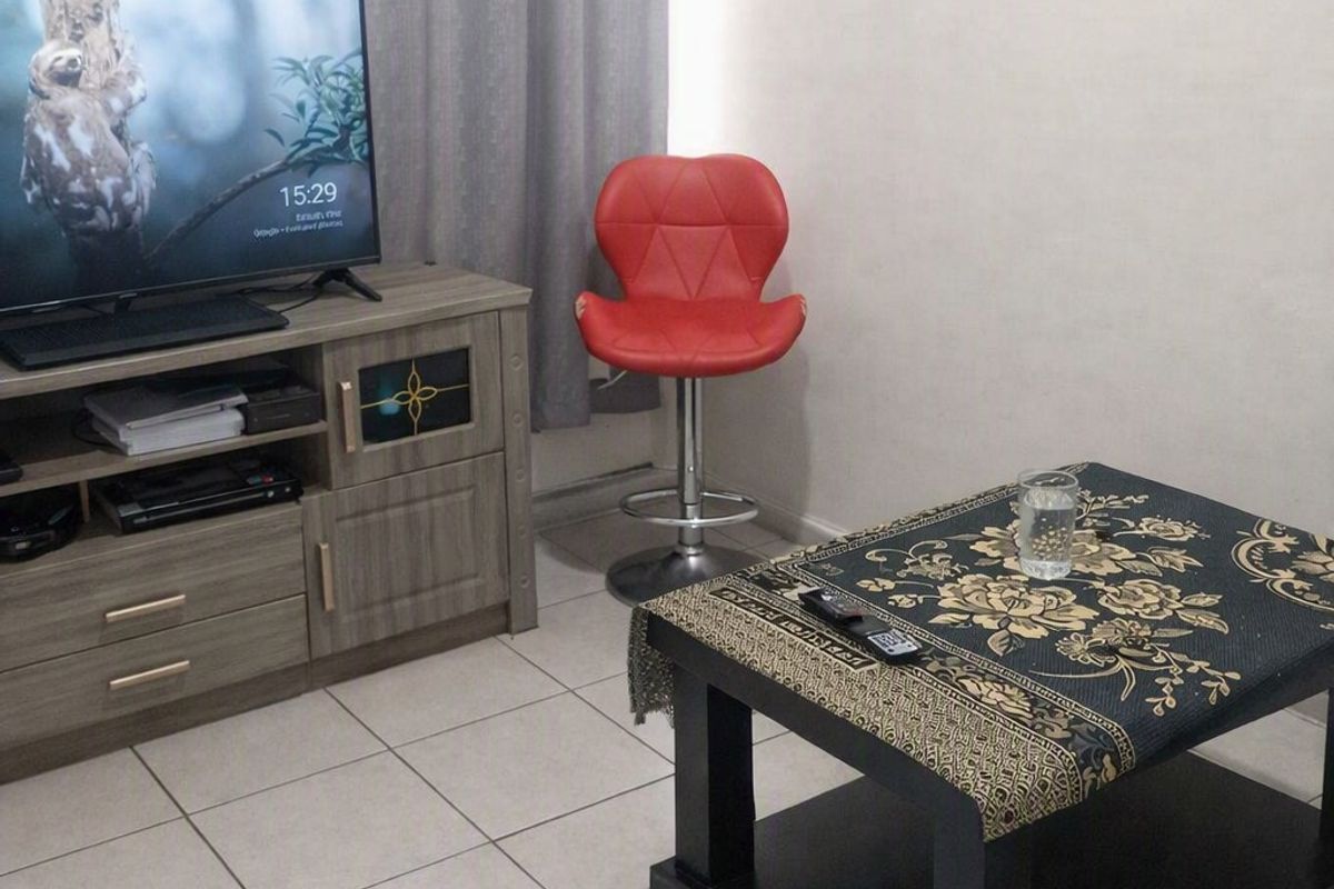 A living room area featuring neutral ceramic floor tiles and simple wall finishes.