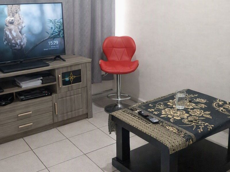 A living room area featuring neutral ceramic floor tiles and simple wall finishes.