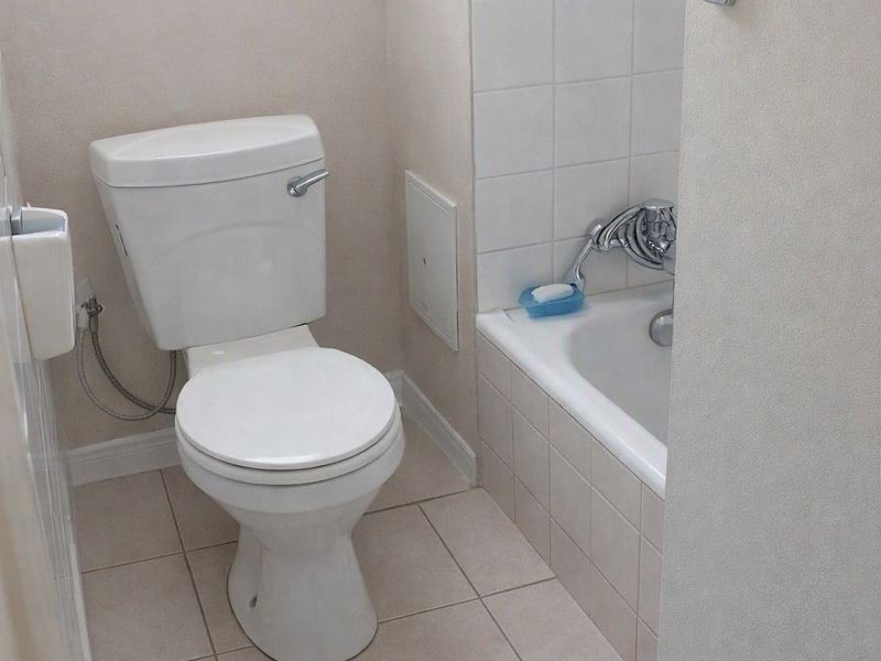 A compact bathroom featuring a standard toilet and a bathtub with tiled finishes, offering a functional layout for an apartment.