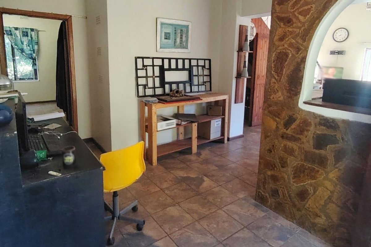 Living area featuring a rustic stone feature wall, ceramic tile flooring, and an open archway leading to adjacent rooms.