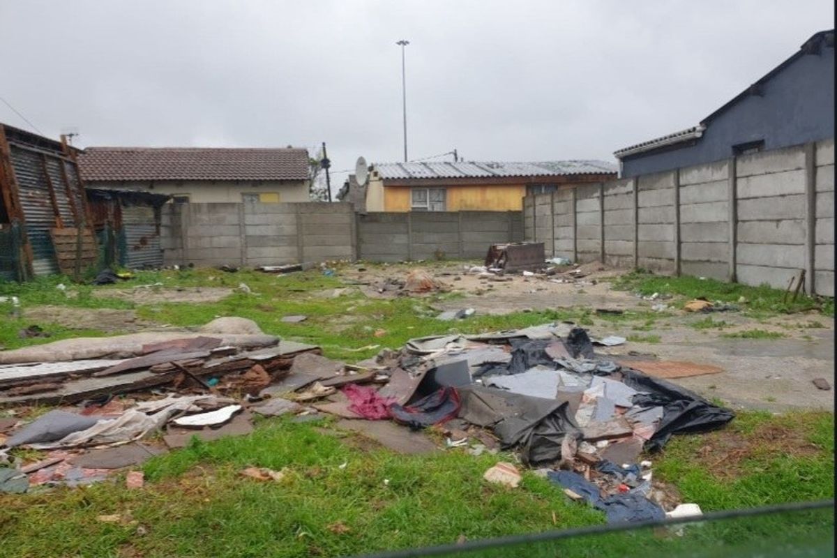 A vacant residential plot enclosed by precast concrete boundary walls, currently requiring significant site clearance and debris removal.