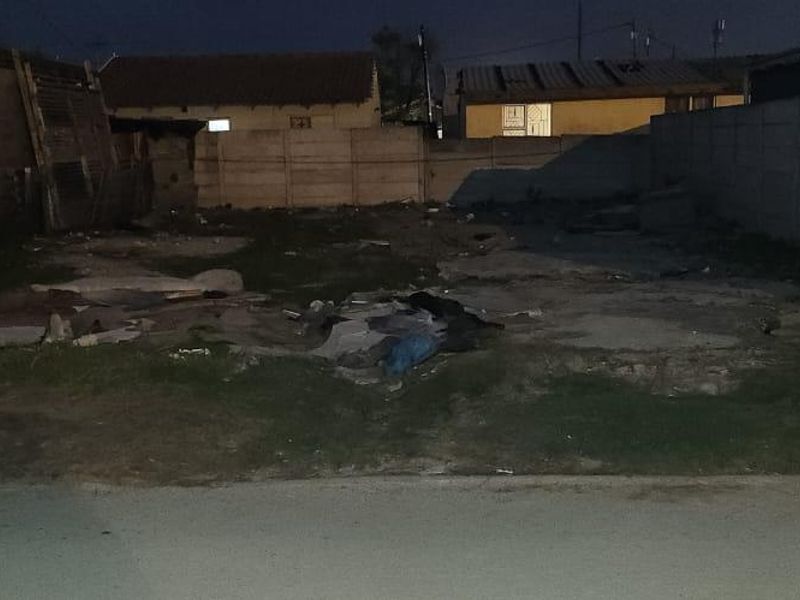 Vacant residential plot featuring a concrete slab foundation and enclosed by precast concrete boundary walls, requiring site clearing and development.