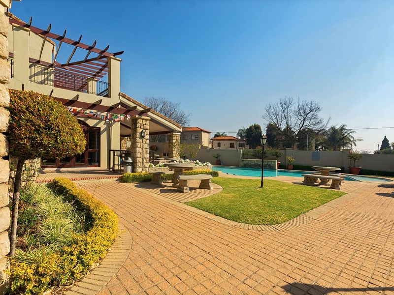 Spacious outdoor entertainment area featuring a swimming pool, paved patio, and a timber pergola attached to the main residence.