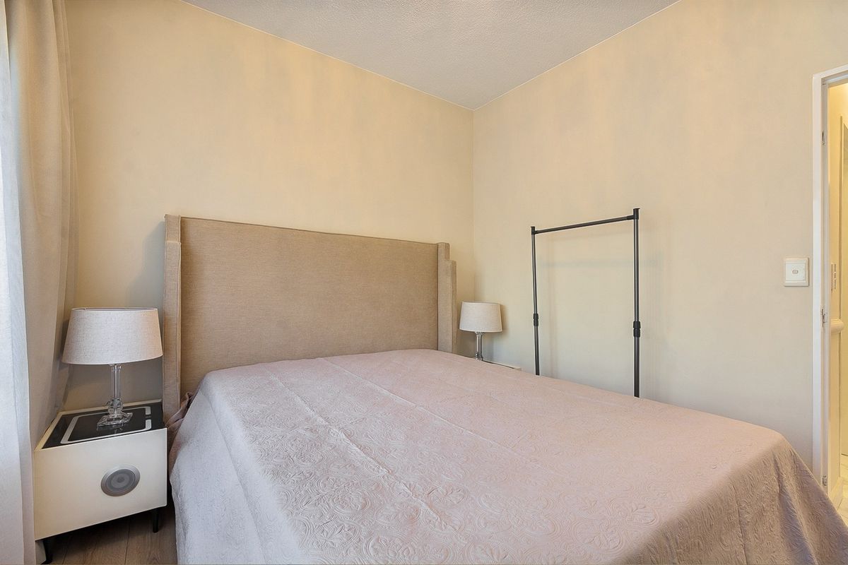 A neutrally decorated bedroom featuring a clean layout with standard electrical fixtures and access to an adjacent room.