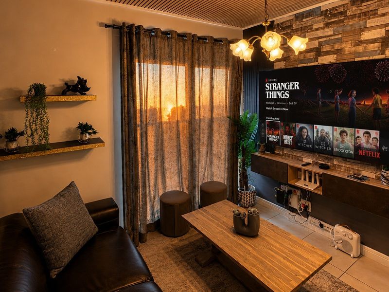 Cozy living room featuring a unique slatted timber ceiling, a textured feature wall, and a custom built-in media console with integrated lighting.