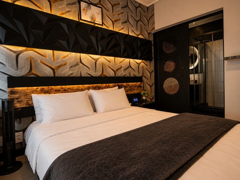 Modern bedroom featuring a striking textured feature wall with integrated LED lighting and convenient access to an en-suite bathroom.