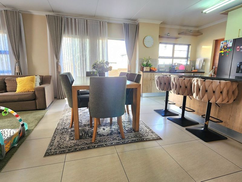 Spacious open-plan living and dining area featuring a modern kitchen with a breakfast island, tiled floors, and large sliding doors leading to the exterior.
