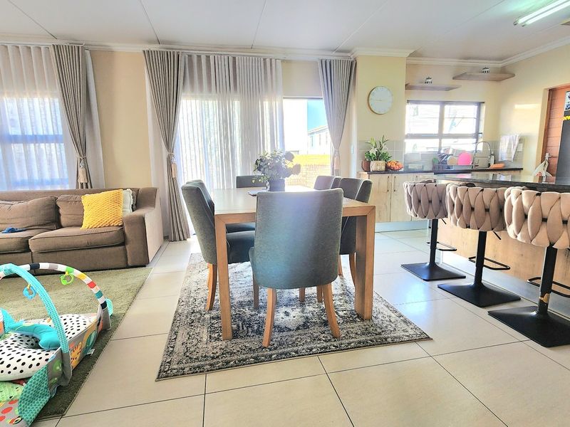 Spacious open-plan living and dining area featuring tiled floors, a modern kitchen with an island, and large sliding doors leading to the exterior.